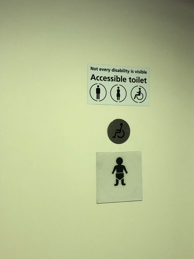 WC-tilan ovi, jossa sukupuoli- ja esteettömyyssymbolit.